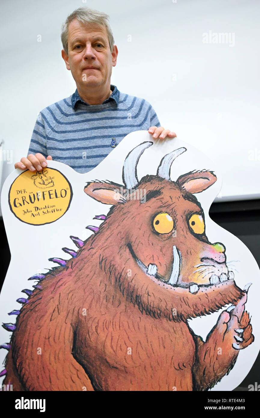 01. März 2019, Nordrhein-Westfalen, Köln: Illustrator Axel Scheffler steht hinter der Pappe mit einem grüffelo während der Präsentation der Sondermarke für seine Schöpfung "Der Grüffelo". Scheffler ist einer der erfolgreichsten Bilderbuchillustratoren weltweit. Foto: Henning Kaiser/dpa Stockfoto