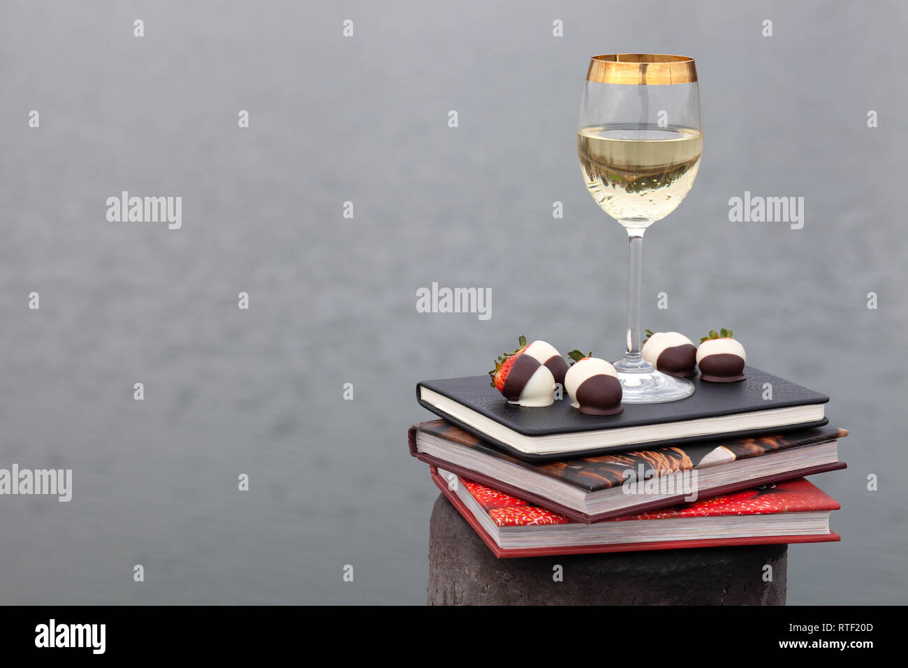 Weingläser und Erdbeeren auf Bücher durch das Wasser Stockfoto