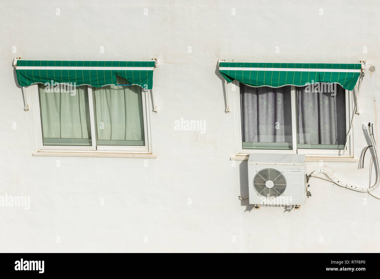 Zwei Fenster mit Rollladen und Klimaanlage an einem heißen Sommertag in Spanien geschlossen. Stockfoto