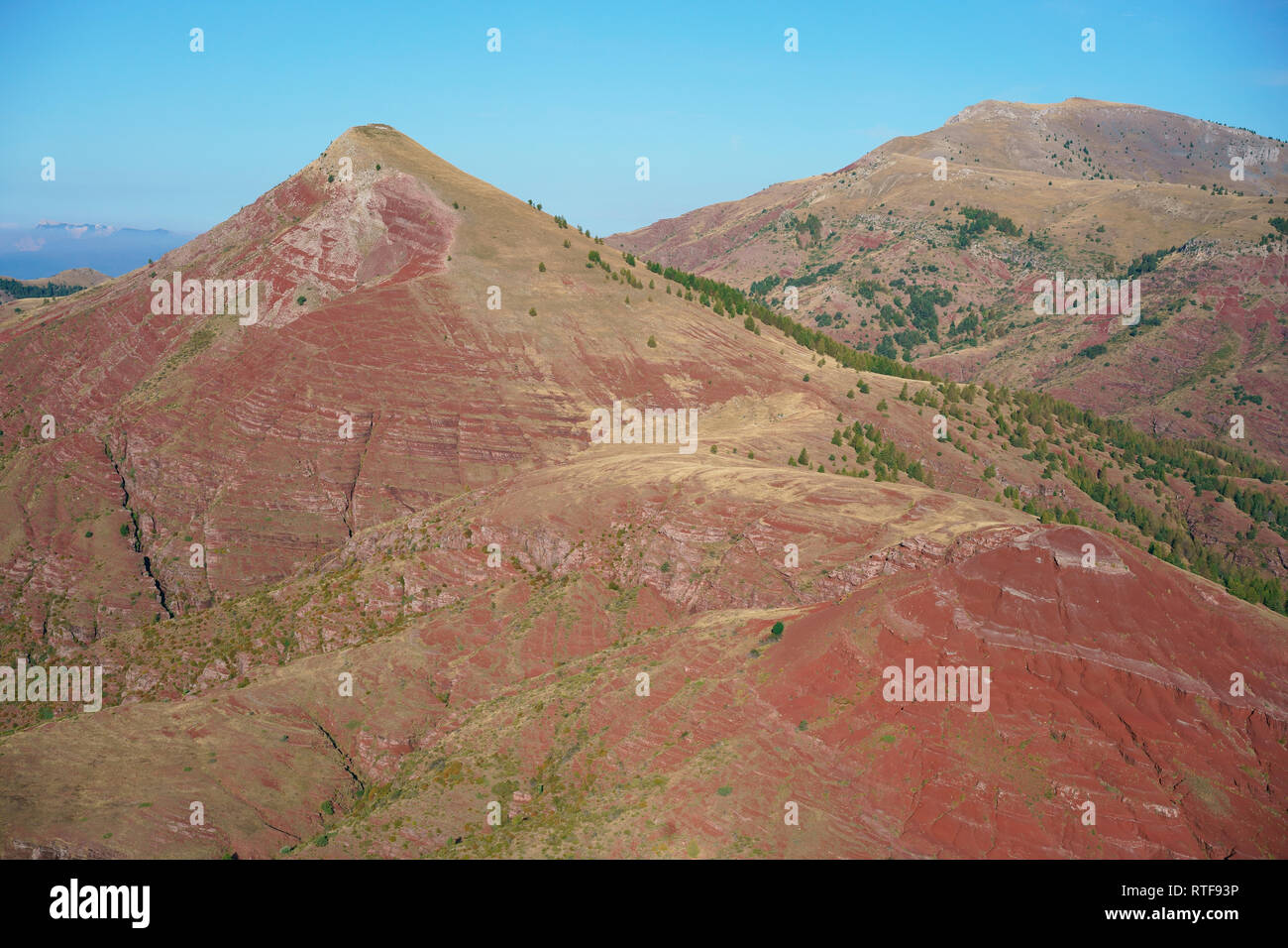 LUFTAUFNAHME. Ungewöhnliche Landschaft aus rotem Felsen in den Alpen. Tête de Rigaud (links) und Dome de Barrot (rechts). Rigaud, Alpes-Maritimes, Frankreich. Stockfoto