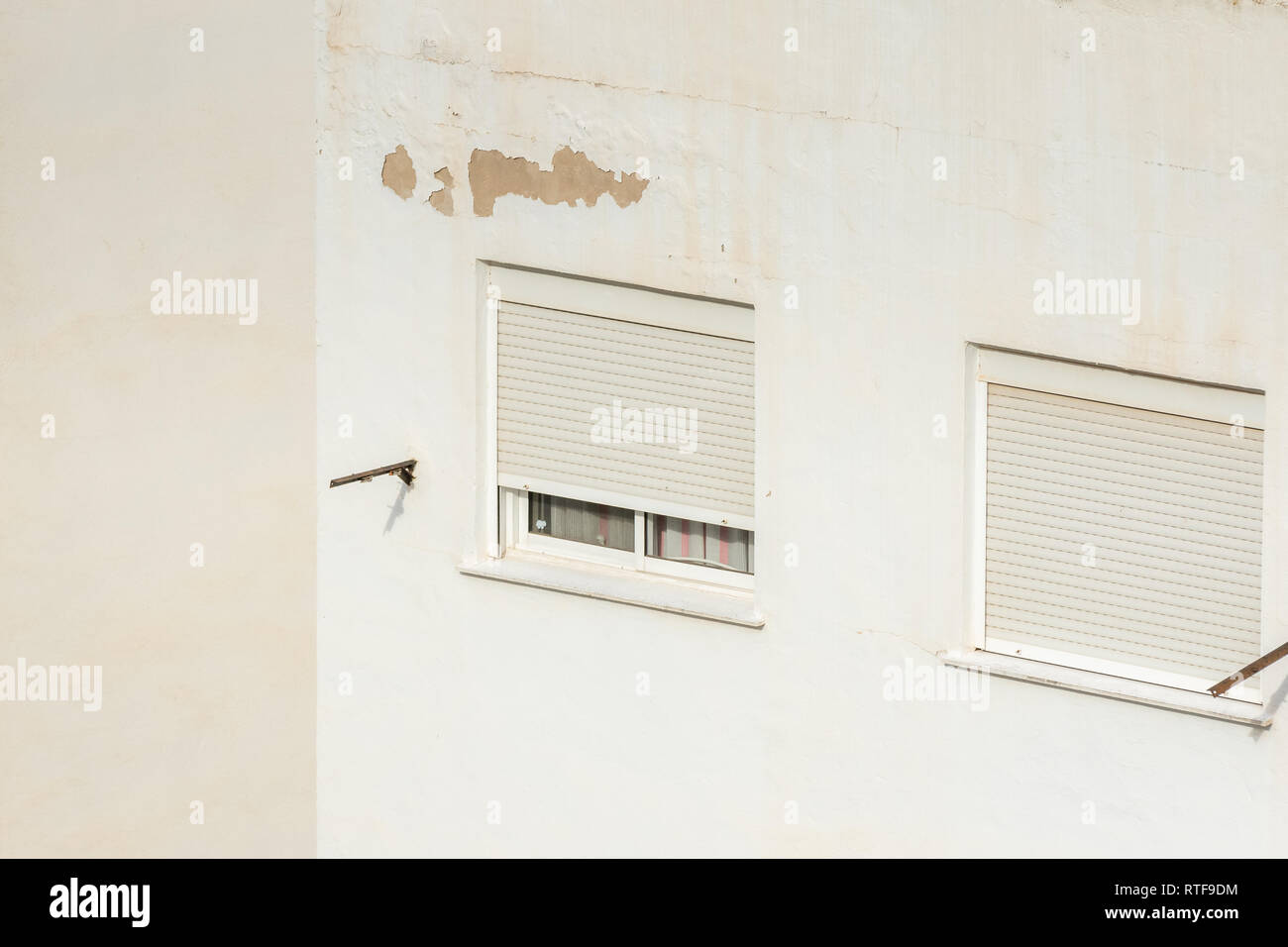 Zwei Fenster mit Rollläden an einem heissen Sommertag in Spanien geschlossen. Auf der weißen Wand isoliert. Stockfoto