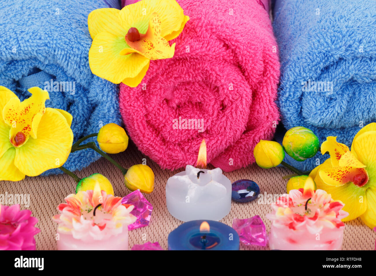 Bad mit Handtüchern, Kerzen und Blumen auf Bambus Hintergrund gesetzt. Stockfoto