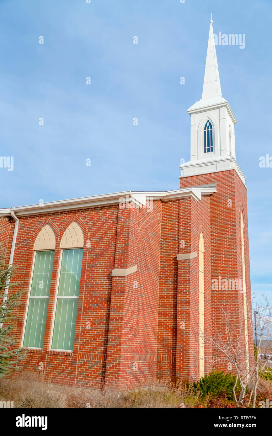 Kirche mit gewölbten Fenstern und weißen Turm. Außenansicht einer Kirche mit Red brick wall gegen den blauen Himmel mit dünnen Wolken. Die Kirche hat reflecti Stockfoto
