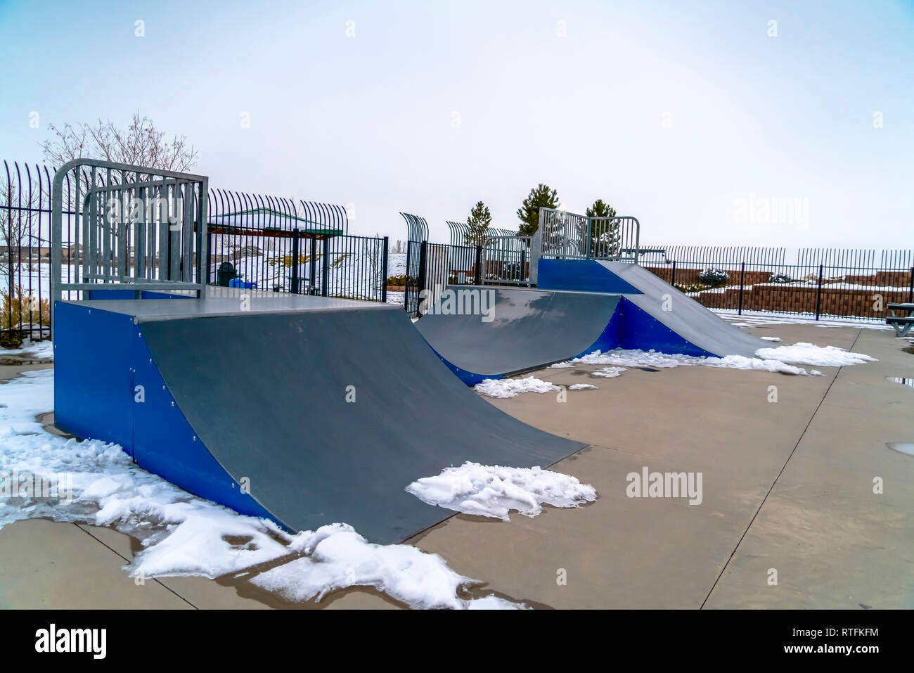 Skateboard Rampen und schmelzende Schnee an einem Skatepark. Skate park mit  schmelzender Schnee rund um die skateboarding Rampen. Im Hintergrund ist  ein Winter landscap Stockfotografie - Alamy