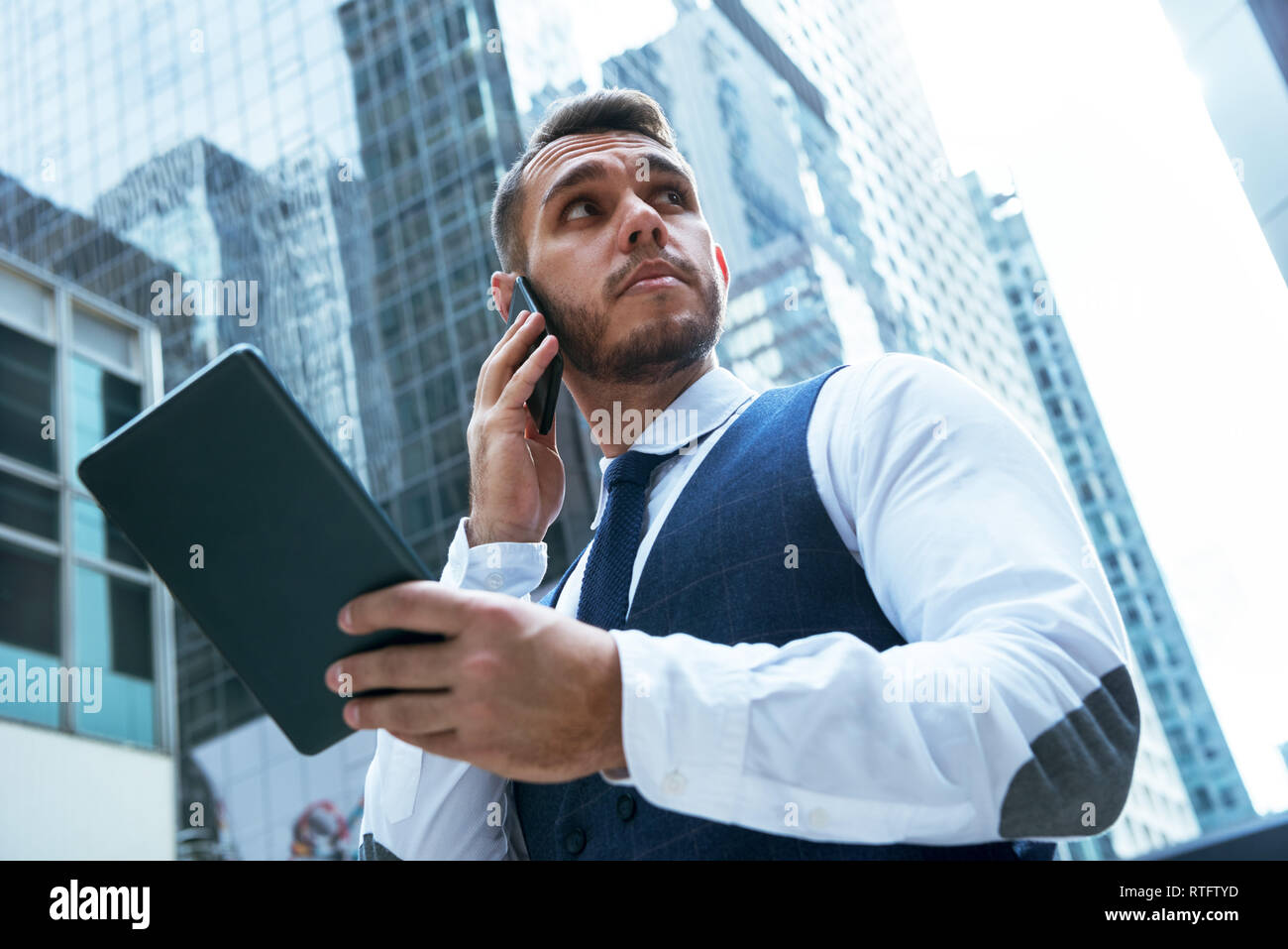 Geschäftsmann mit Tablet-PC spricht über das Telefon in der großen Stadt Stockfoto
