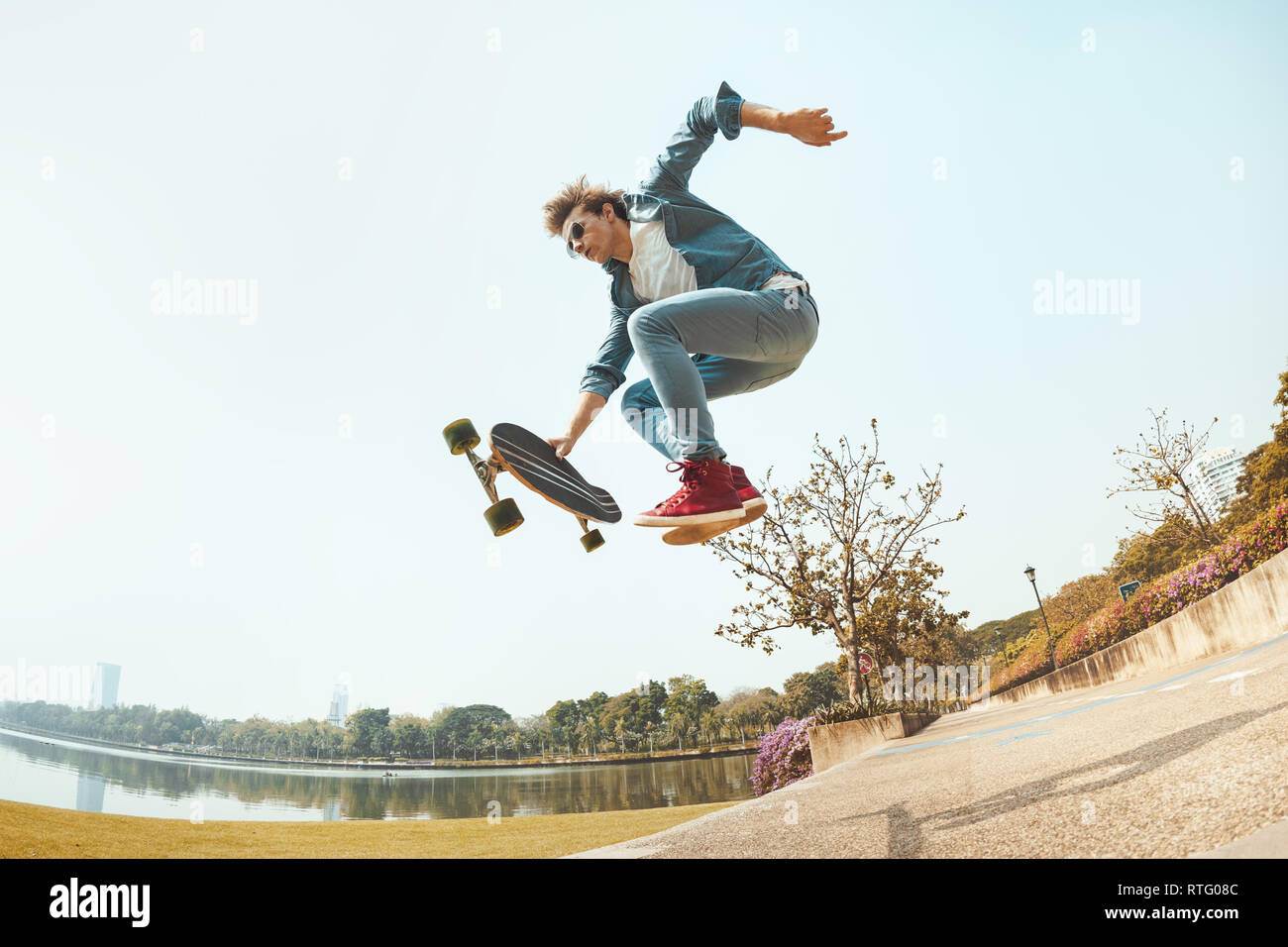 Mann hipster springt mit Skateboard in Park Stockfoto