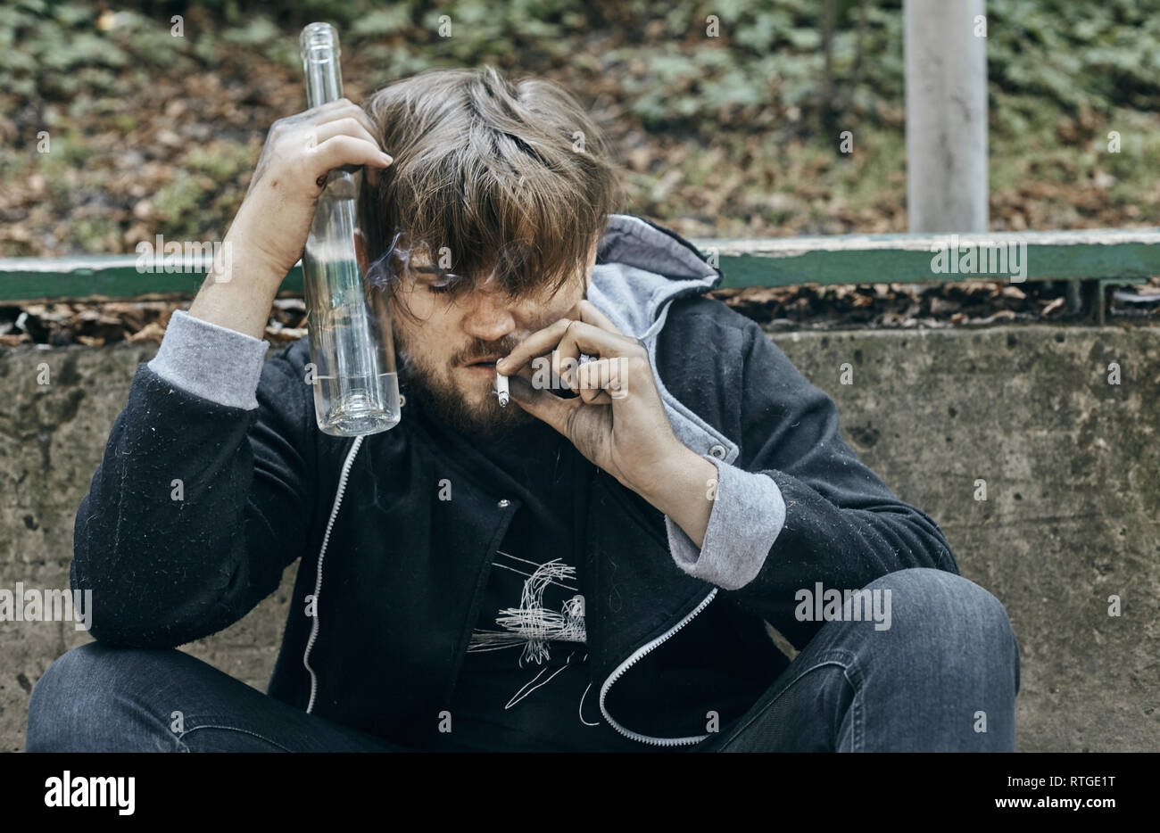 Der Mann hält ein Glas Wodka. Betrunkene Jugendliche. (Alkoholismus, Schmerz, Leid, Verzweiflung, Hoffnungslosigkeit, soziale Problem der Abhängigkeit Konzept) Stockfoto