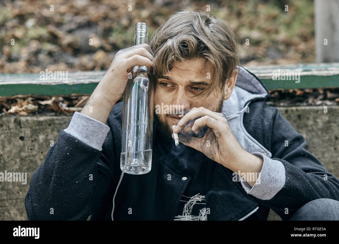 Der Mann hält ein Glas Wodka. Betrunkene Jugendliche. (Alkoholismus, Schmerz, Leid, Verzweiflung, Hoffnungslosigkeit, soziale Problem der Abhängigkeit Konzept) Stockfoto