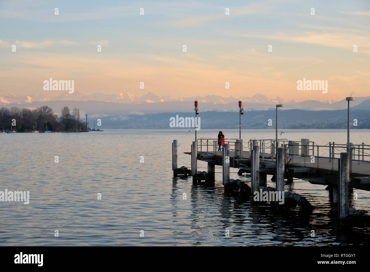 Blick Ÿber den ZŸrichsee mit Bootsanleger in die schneebedeckten Schweizer Alpen. Stockfoto