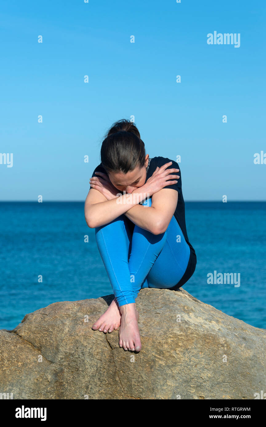 Deprimiert Frau sitzen auf den Felsen am Meer Stockfoto