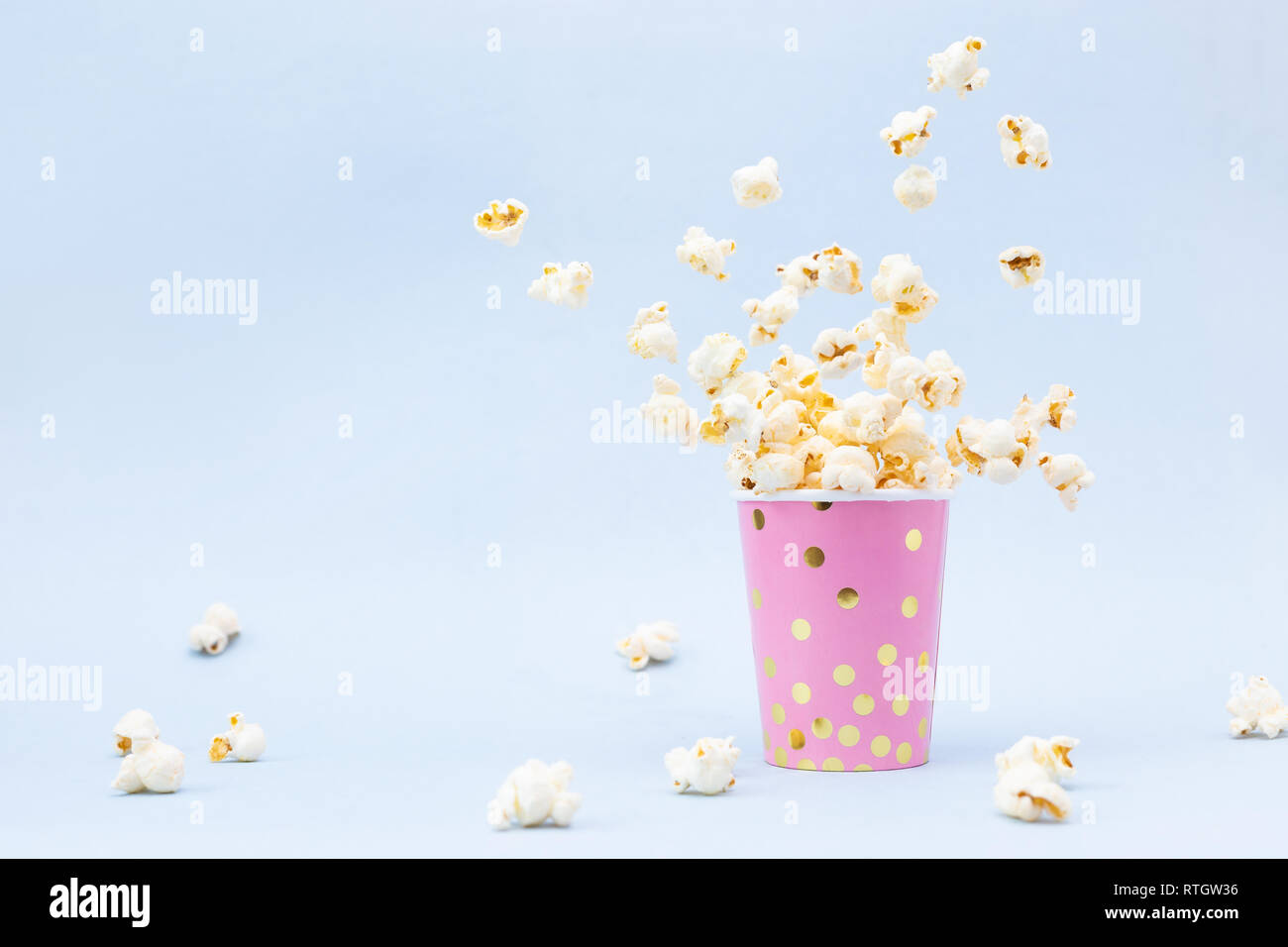Flying Popcorn in einem hellen Glas und auf blauem Hintergrund. Platz kopieren Stockfoto
