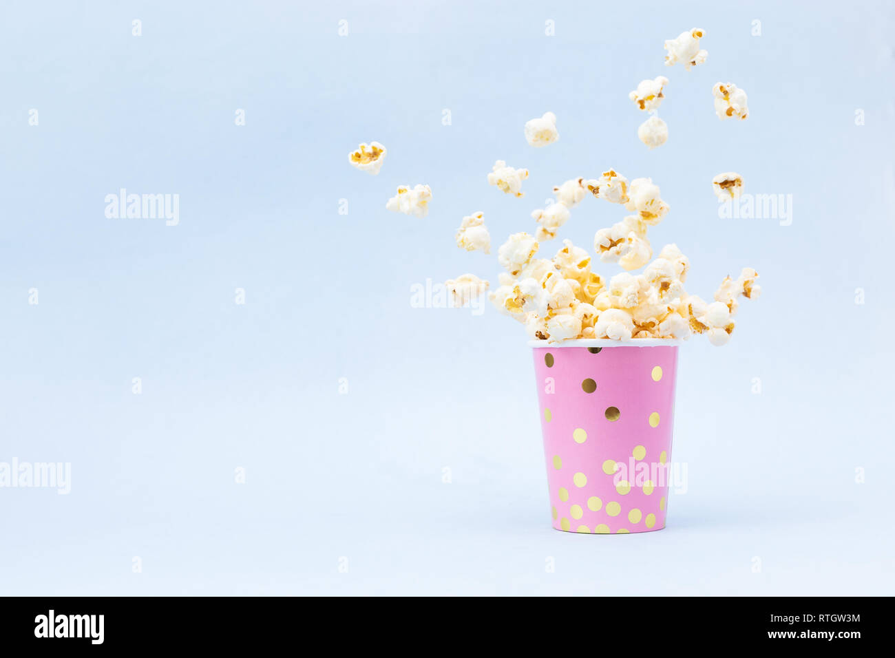 Flying Popcorn in einem hellen Glas und auf einem rosa Hintergrund. Platz kopieren Stockfoto