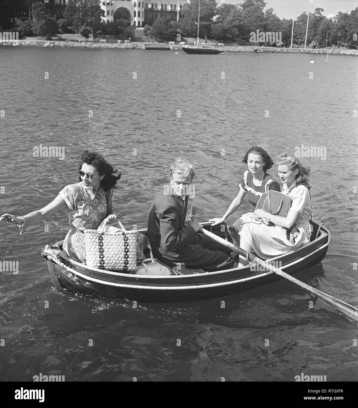 1940 Sommer. Vier Personen sitzen in einem sehr kleinen Ruderboot. Sie sind alle hübsch im Sommer Kleider und Picknick Taschen gekleidet. Der Mann Zeilen. Foto Kristoffersson ref AC 102-3. Schweden 1946 Stockfoto