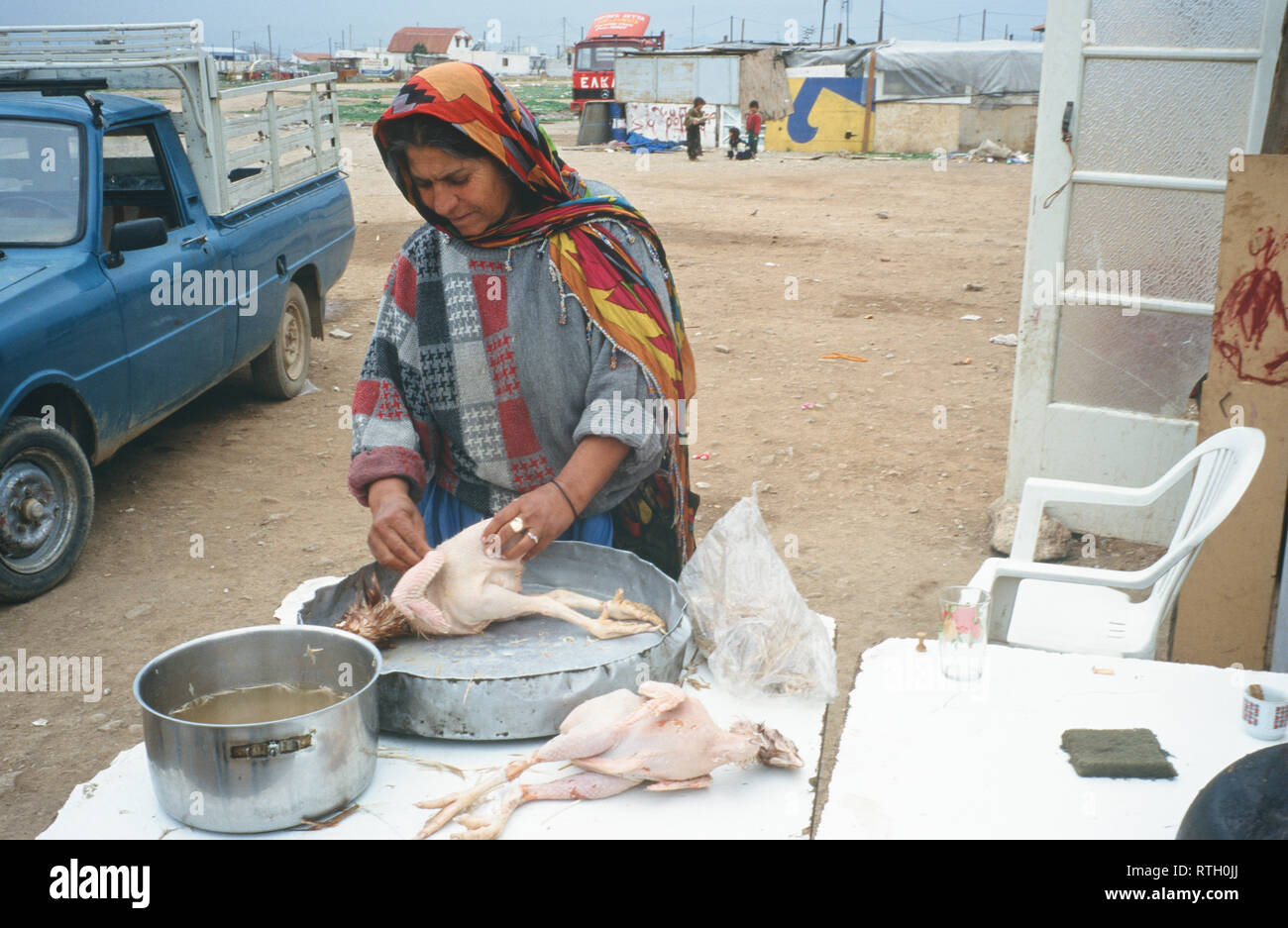 Eine Zigeunerin bereitet ein Huhn für Abendessen im Aspropyrgos Zigeunerlager, Athen, Griechenland. Stockfoto