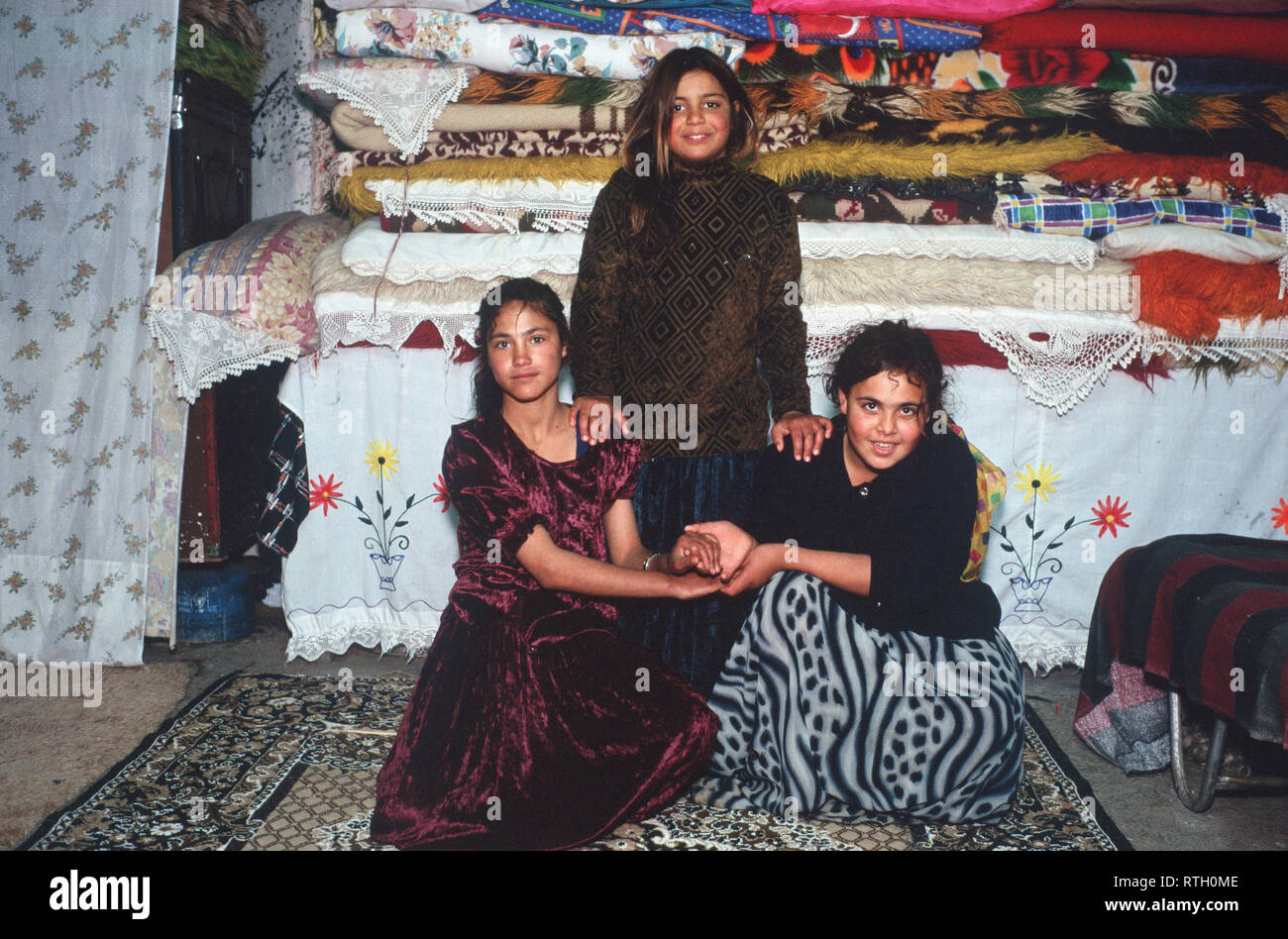 Drei zigeunerinnen vor der Braut ihrer Mutter trousseau in der Hütte ihrer Familie an der Aspropyrgos Zigeunerlager, Athen, Griechenland. Stockfoto