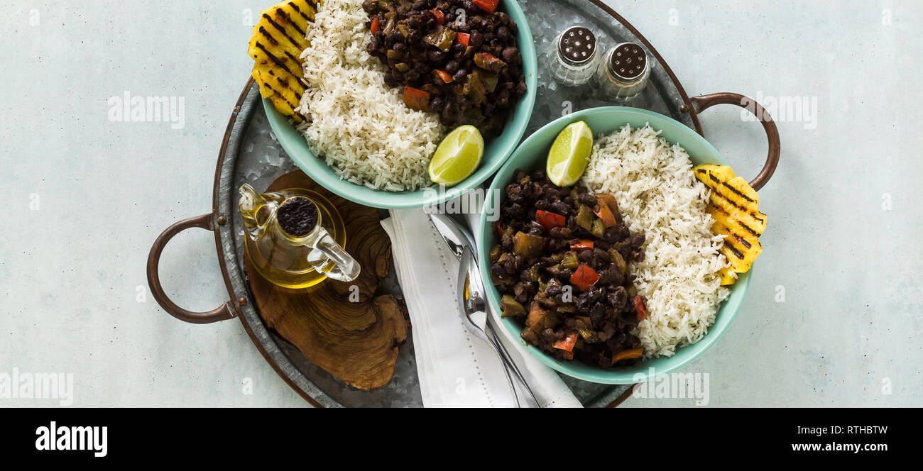 Banner der Kubanischen Reis und schwarze Bohnen Teller mit gegrillter Ananas. Gesund Vegan karibisches Essen für die ganze Familie, Party oder Restaurant Menü Stockfoto