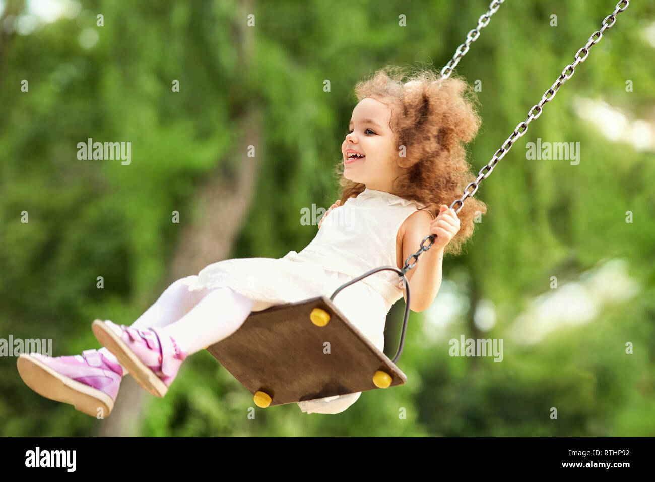 Kind Schwingen auf der Schaukel am Spielplatz im Park. Stockfoto