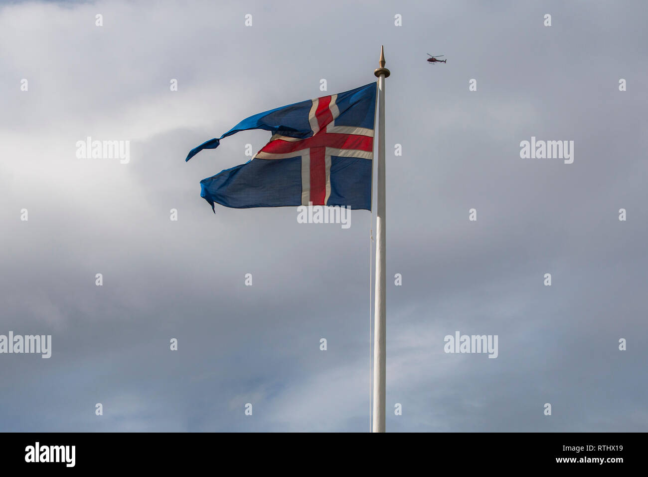 Icleandic Flagge in den bewölkten Himmel, Helikopter fliegen im Hintergrund in der Sommersaison Stockfoto