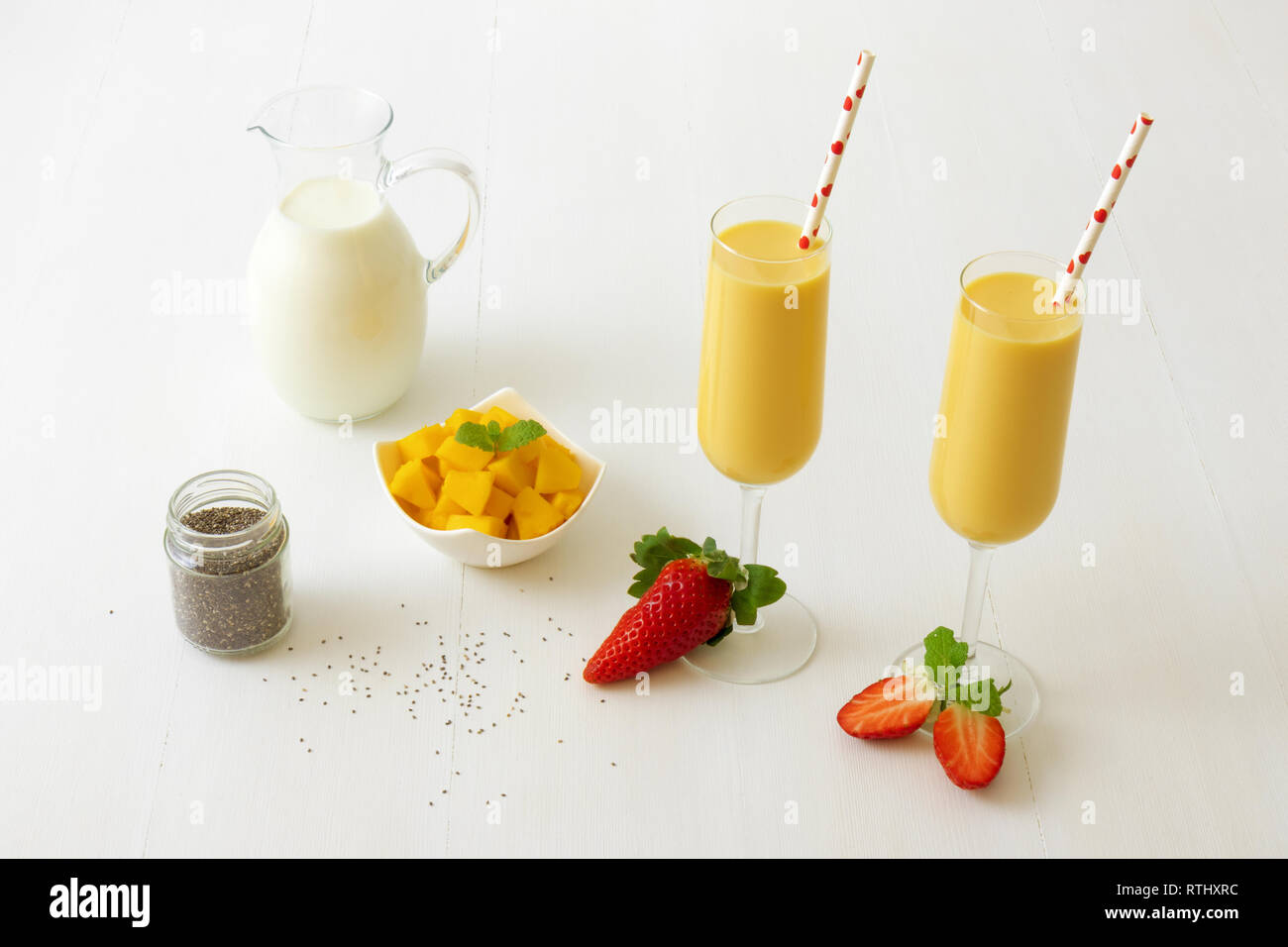 2 Gläser frische Mango Smoothie oder Mango Milchshake mit Milch in Glas  Krug, Chia Samen, Mangostückchen in Porzellan Schüssel und nur wenige echte  Frische Stra Stockfotografie - Alamy