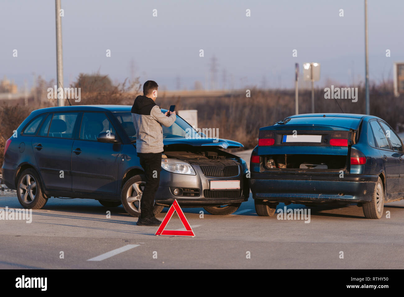 Ein Mann mit einem Smart Phone ein Foto von den Schaden an seinem Auto durch einen Autounfall verursacht zu nehmen Stockfoto