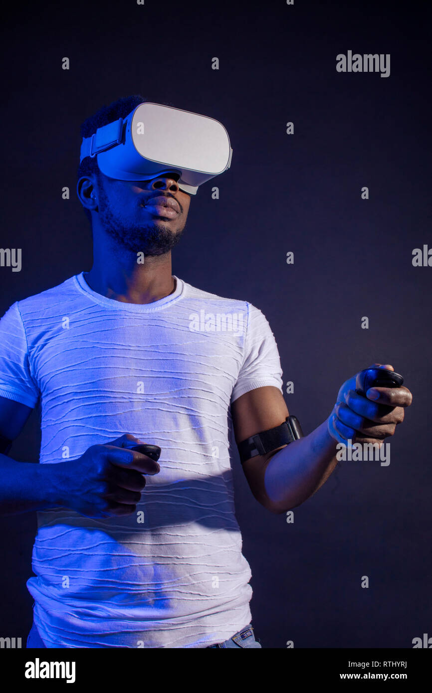 Technologie, Unterhaltung, Spiele, Cyberspace und Personen Konzept. Ernsthafte Dunkelhäutige Spieler tragen weiße T-Shirt und weiße Moderne 3-D-Brille. Blac Stockfoto