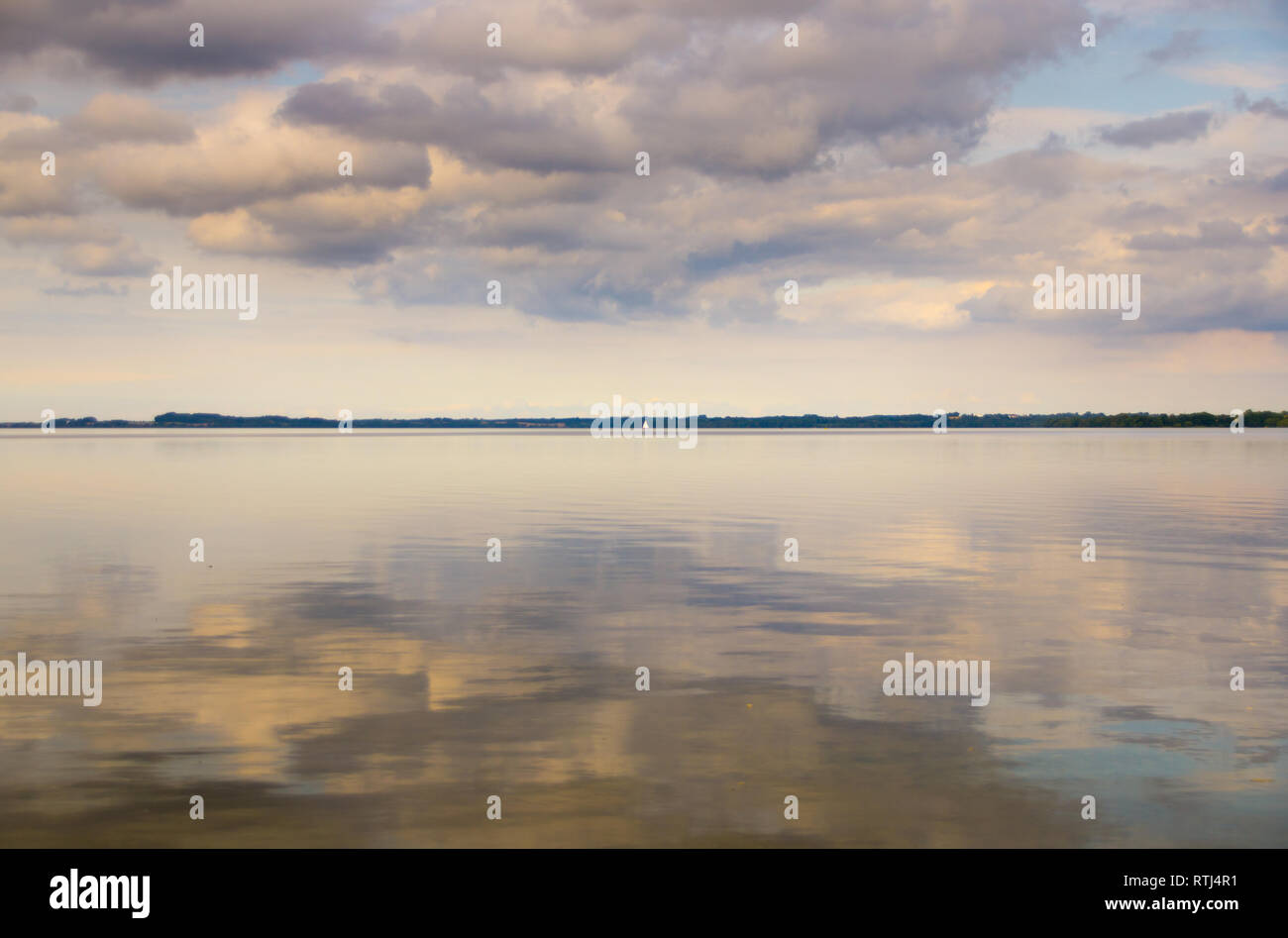 Wolken des Himmels auf einem See mit einer zentralen Linie der Wald spiegelt Stockfoto