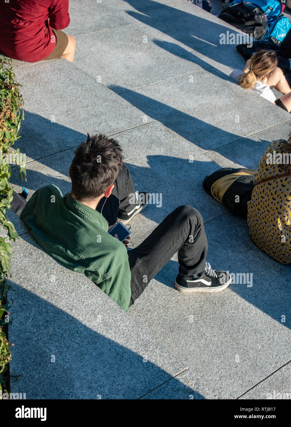 Aufnahme von oben einsamer Mann sitzt auf Schritte entspannend mit seiner mobilen Stockfoto