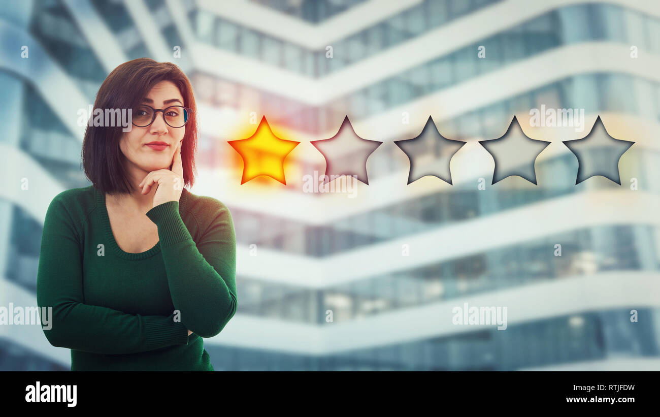 Skeptiker junge Frau mit der Hand unter dem Kinn, das enttäuscht 1 Stern vergeben. Schlecht und schlechter Service Konzept. Negative Gefühle, di Stockfoto