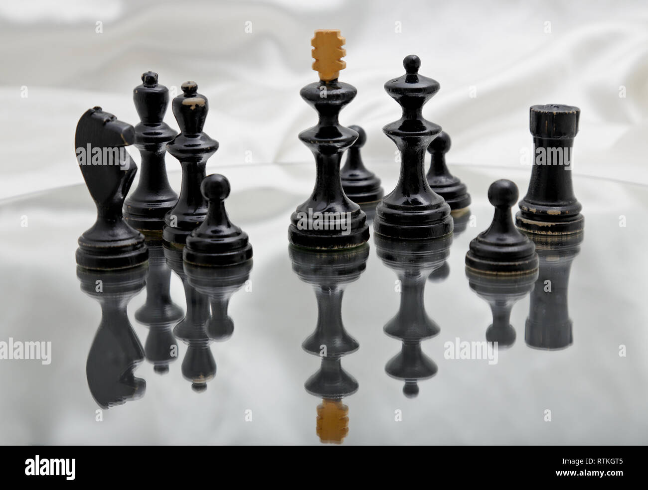 Schwarze Schachfiguren auf einem Spiegel mit glänzenden weißen Hintergrund Stockfoto