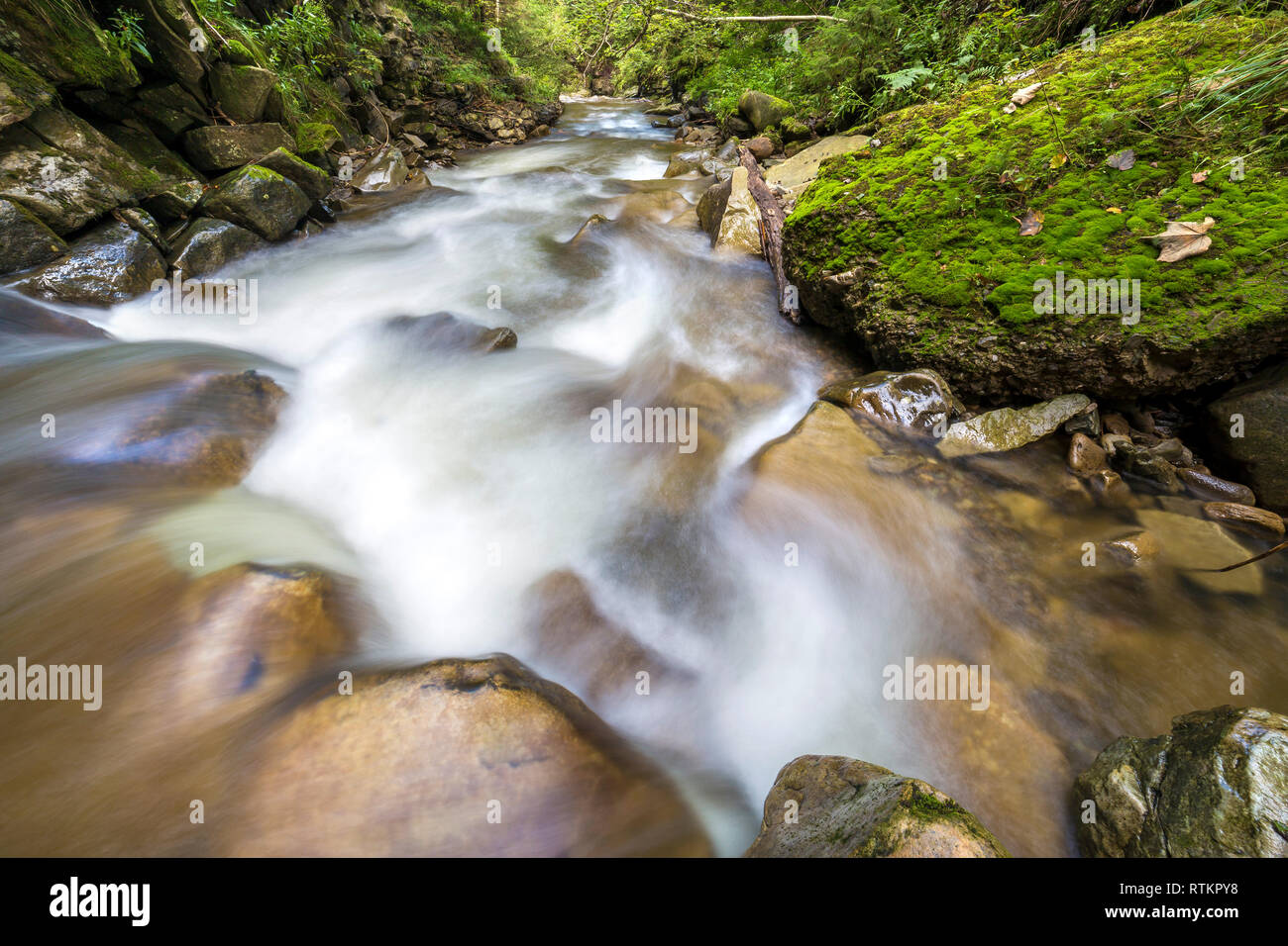 Schnell fließenden Fluss Bach mit seidig glatt das Wasser fällt aus großen Steinen in schönen Wasserfällen auf hellen Sommertag. Stockfoto