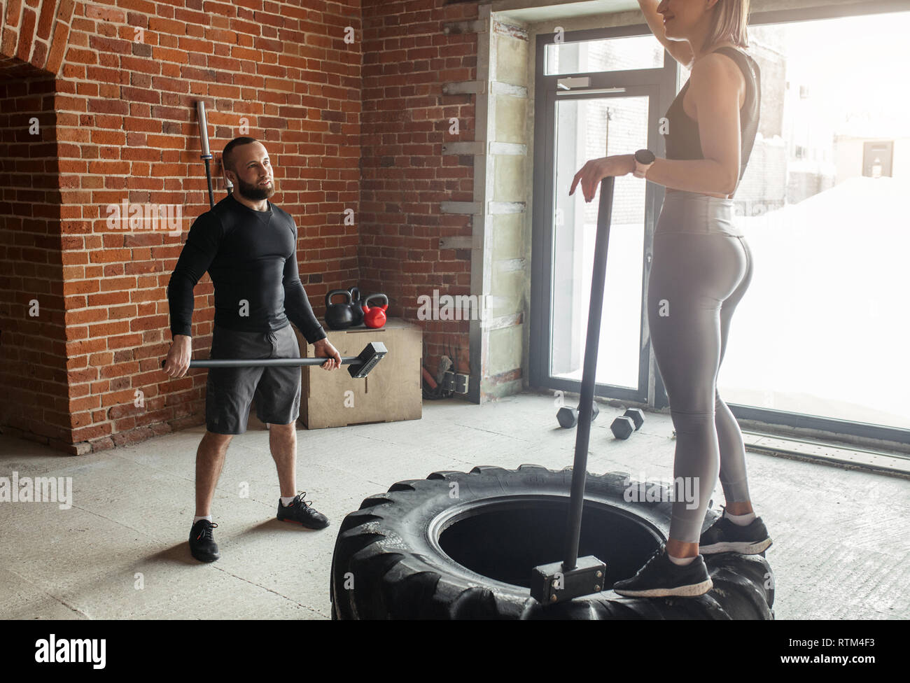 Athletisch paar Arbeiten in crossfit Studio, üben Hammer Knall auf LKW-Reifen, liegen auf dem Boden. Stockfoto