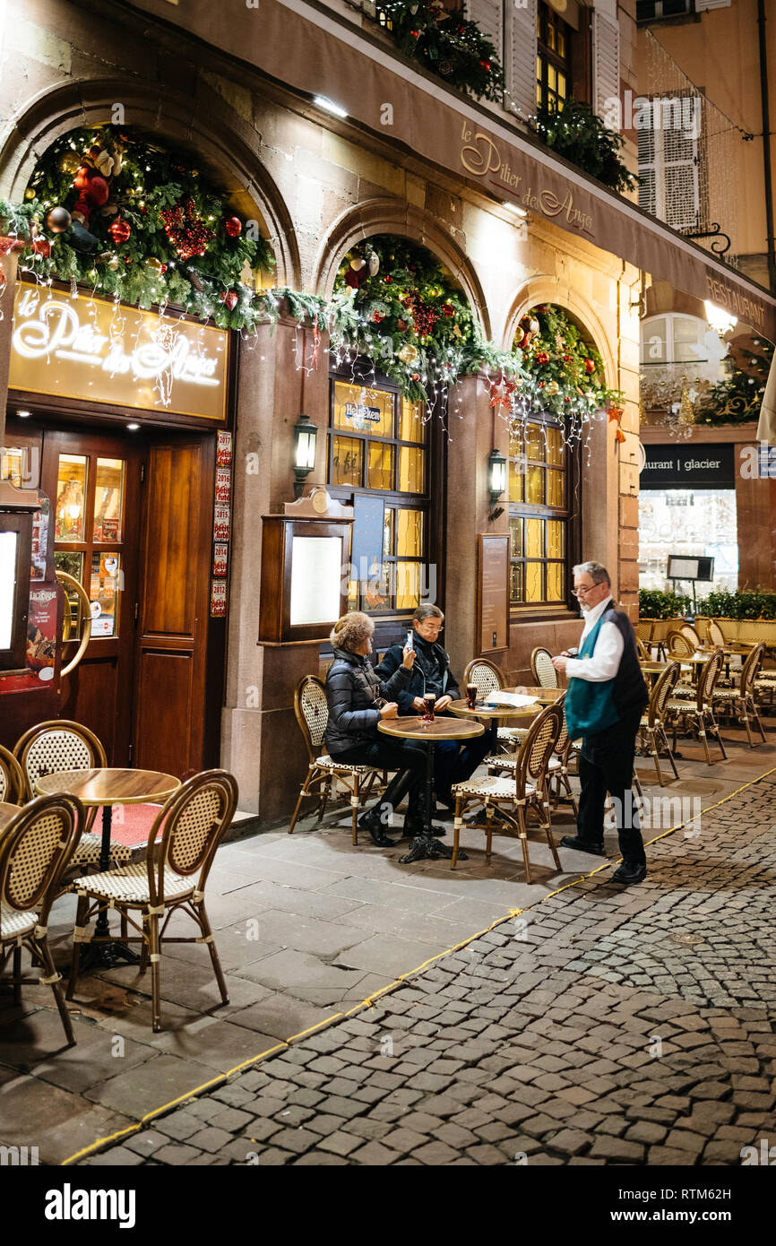 Straßburg, Frankreich - 21.November 2017: Le Pilier des Anges französisches  Restaurant auf der berühmten Rue Merciere mit Senior paar Essen im Café  draußen die Zeche zahlen an den Kellner Stockfotografie - Alamy