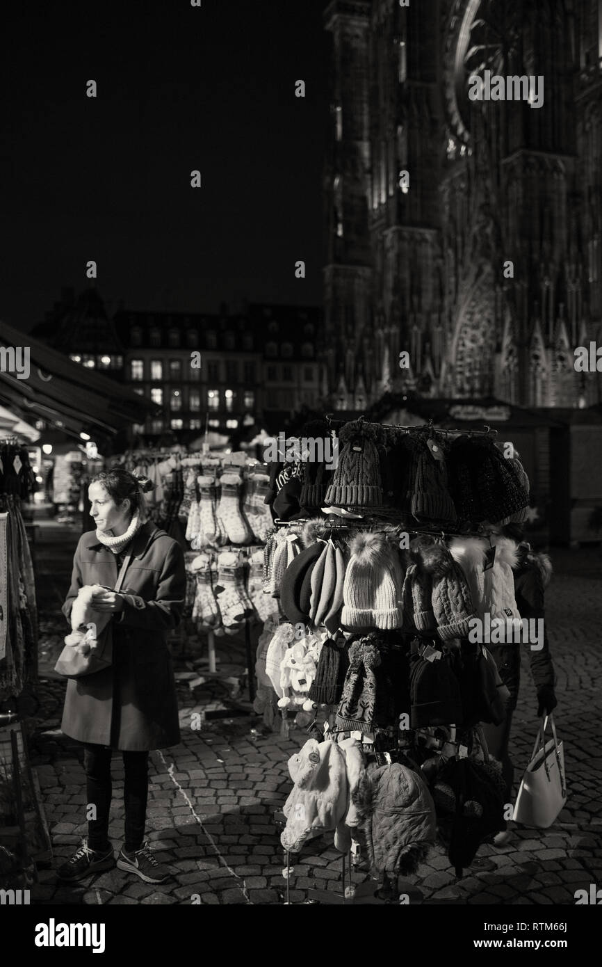 Straßburg, Frankreich - 21 November, 2017: weiblich Frau Wahl gestrickt aus Wolle Mützen und Socken in PLace de la Cathedrale einen Tag vor Weihnachten Markt beginnt - Schwarz/Weiß-Bild Stockfoto