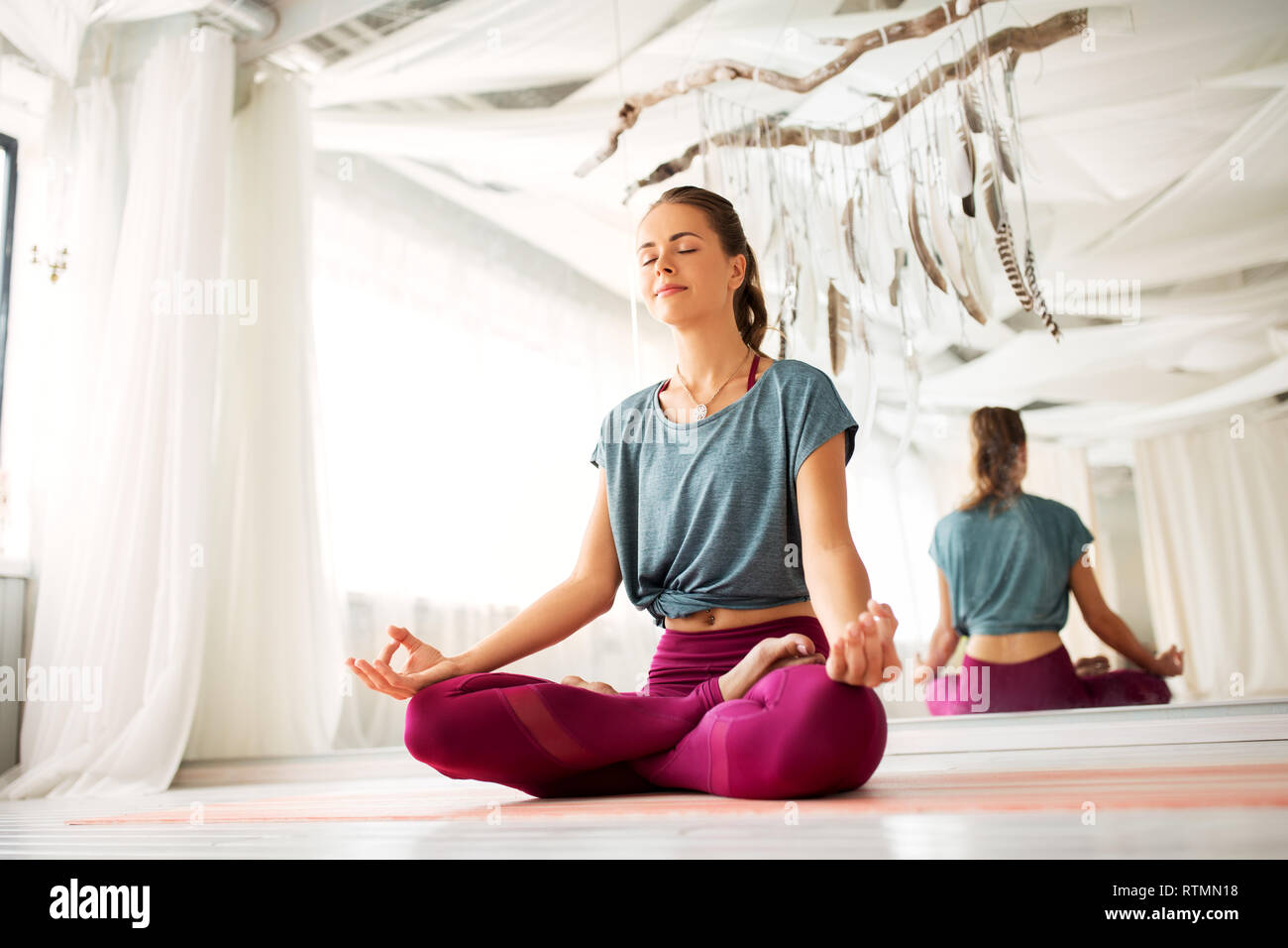 Frau Meditation im Lotussitz auf Yoga Studio Stockfoto