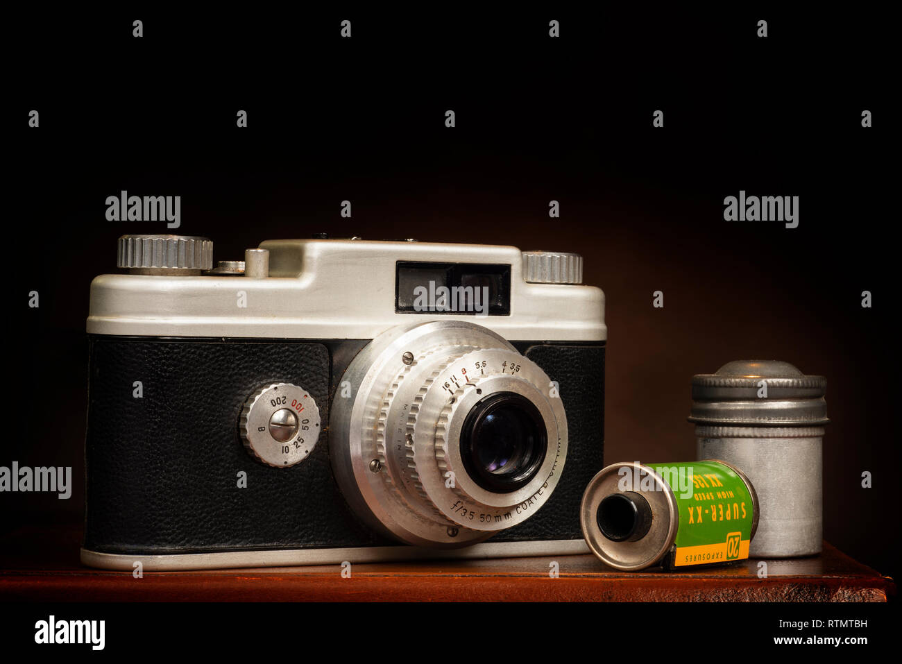 Horizontale Nahaufnahme von einem alten 1950er 35-mm-Kamera und Film auf braunem Hintergrund mit kopieren. Stockfoto