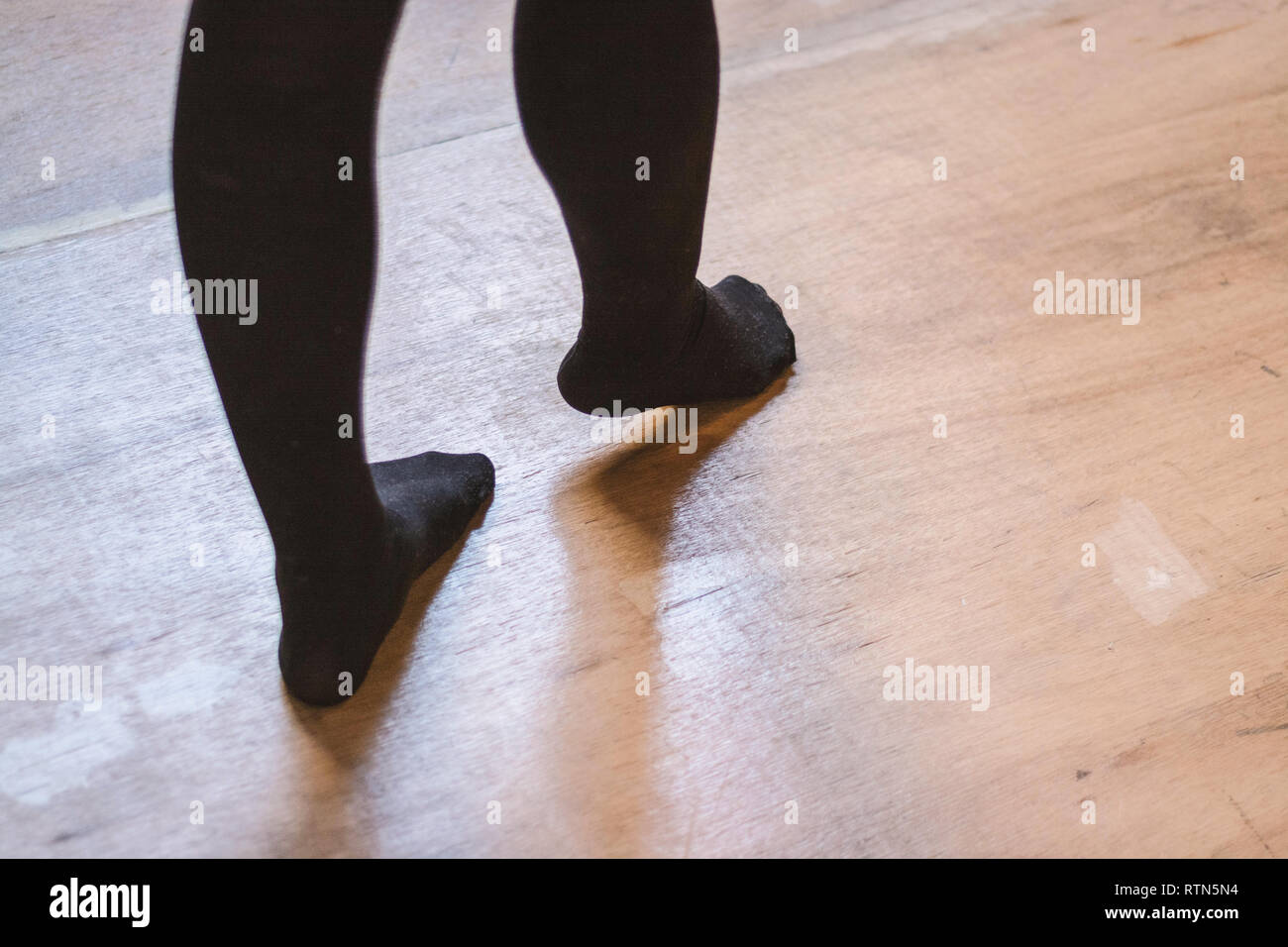 Person zu Fuß auf Holzboden Strümpfe tragen Stockfoto