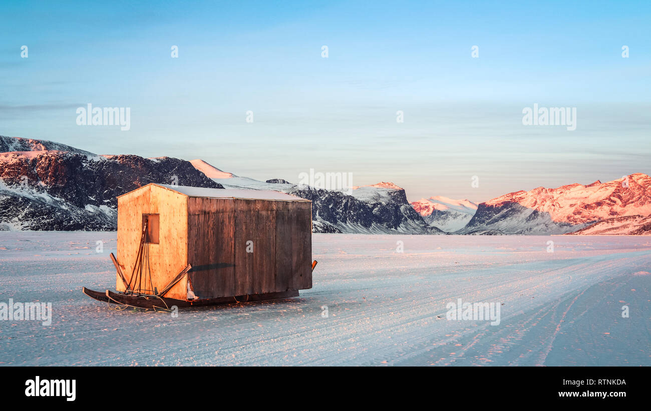 Abgebrochene Angeln shack sitzen auf das gefrorene Meer als die Sonne untergeht. Stockfoto
