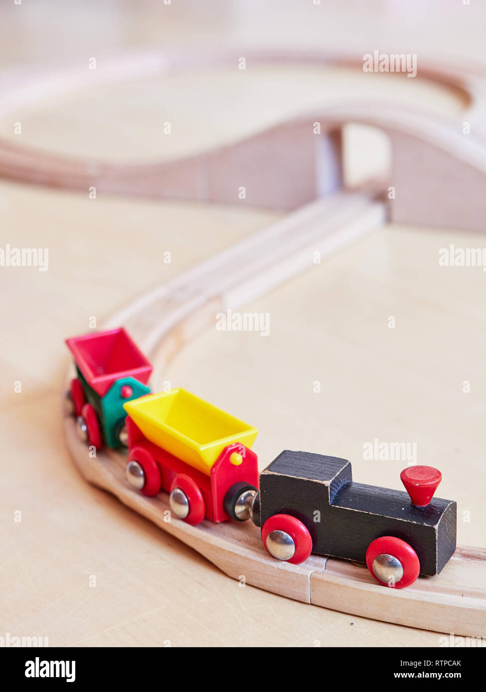 Holzspielzeug Zug, der auf miniatur Titel. Die schwarzen Motor ziehen bunte Autos auf dem Boden. Pädagogische Spielwaren für Kinder im Vorschul- und Art Stockfoto