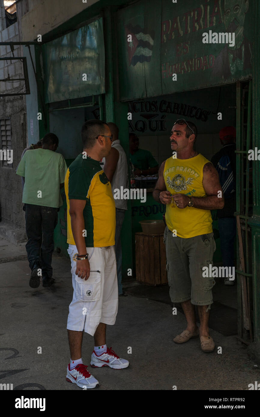 Havanna, Kuba - 21. Januar 2013: Ein Blick auf die Straßen der Stadt mit dem kubanischen Volk. Zwei Männer sprechen vor einem Geschäft. Stockfoto