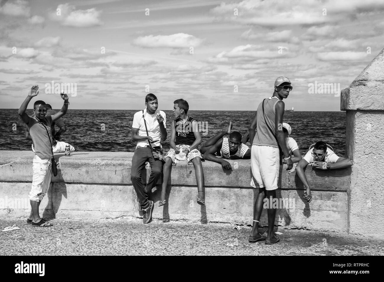 Havanna, Kuba - 22. Januar 2013: Ein Blick auf die Straßen der Stadt mit dem kubanischen Volk. Eine Gruppe von Teenagern entspannt auf seawall Malecon. Stockfoto