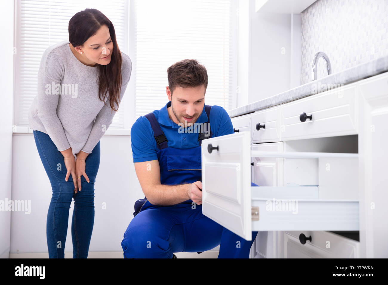 Frau an männlichen Heimwerker Montage von Tür der Schublade in der Küche auf der Suche Stockfoto