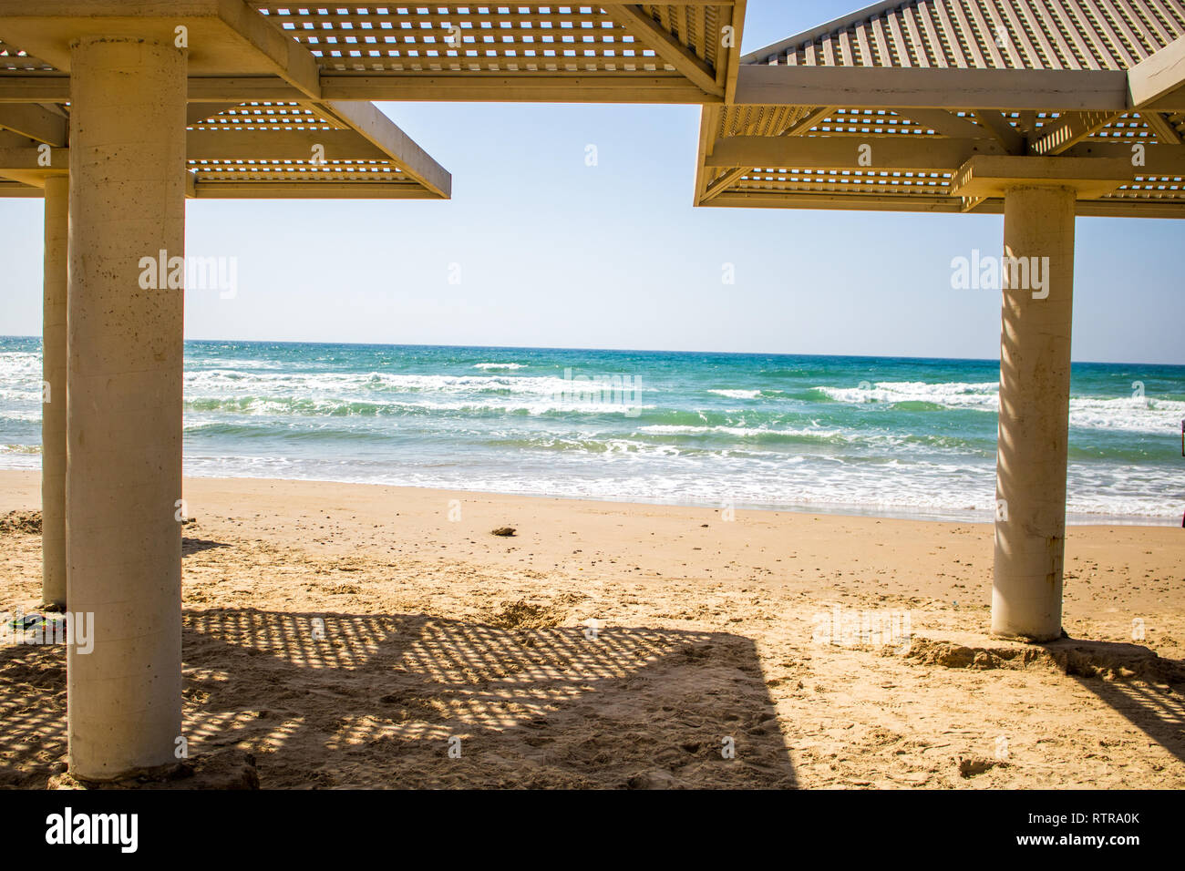 Strand von Tel Aviv, Israel. Sonniges Wetter mit strahlend blauem Himmel und schönen Schatten form Stein Strand Sonnenschirme. Stockfoto