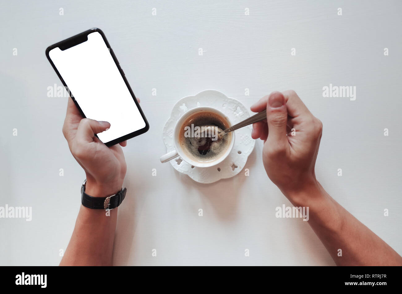 Ansicht von oben Hand eines Espresso in weiße Tasse auf Tabelle mit Smart Phone. Stockfoto