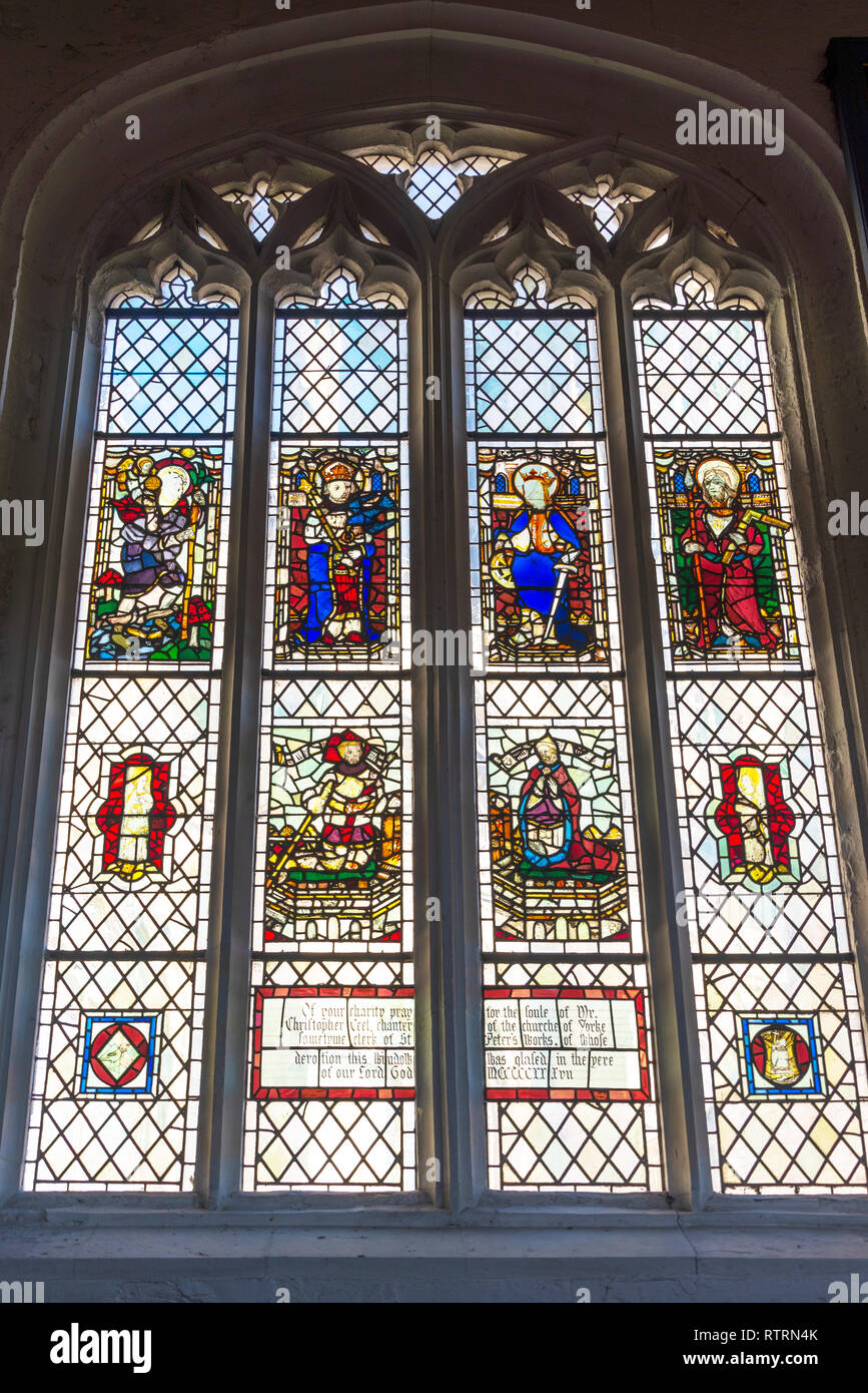 Buntglasfenster von St. Michael le Belfrey Kirche in York. Die bunten Glas zeigt Heiligen und eine Inschrift unten. Stockfoto