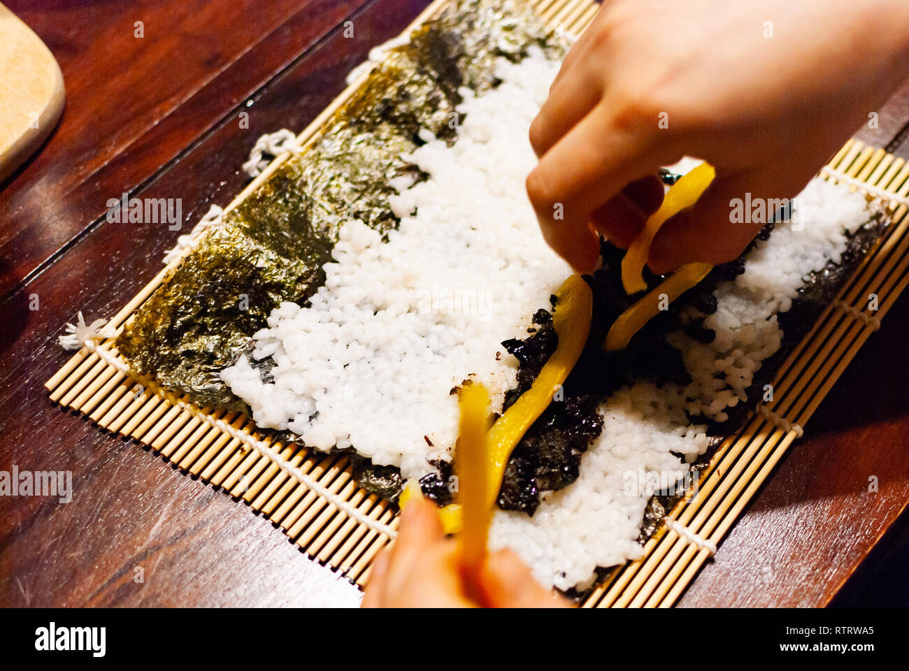 Seitenansicht eines jungen Frauen vorbereiten Hausgemachte vegane Sushi auf einem Holztisch Stockfoto