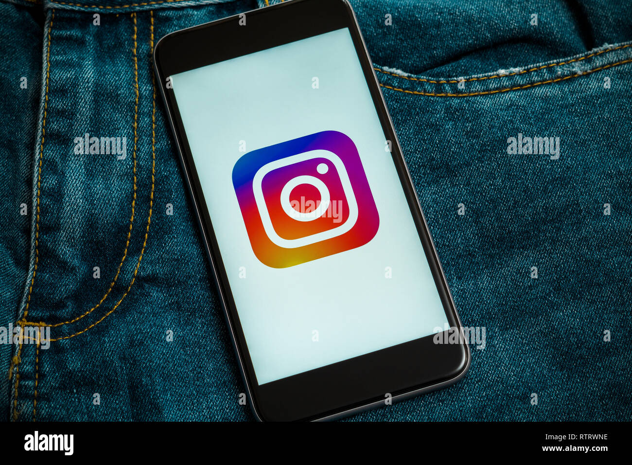 Schwarz mit Logo von social media Instagram auf dem Bildschirm. Social media Symbol. Denim Jeans Hintergrund. Stockfoto