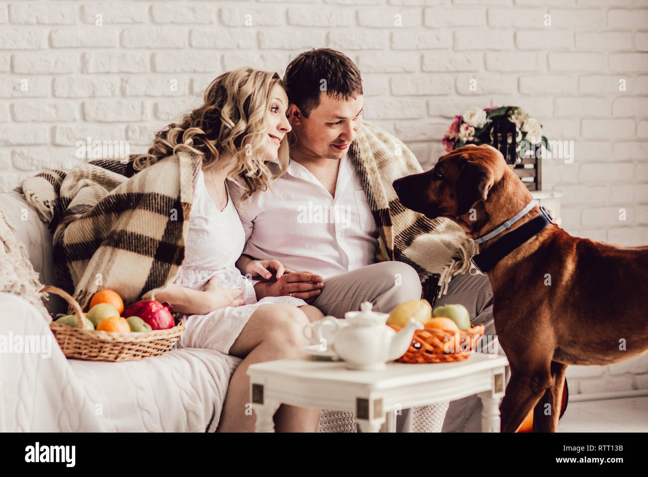 Junges Ehepaar mit ihrem Haustier am Morgen sitzen in einem gemütlichen Wohnzimmer Stockfoto