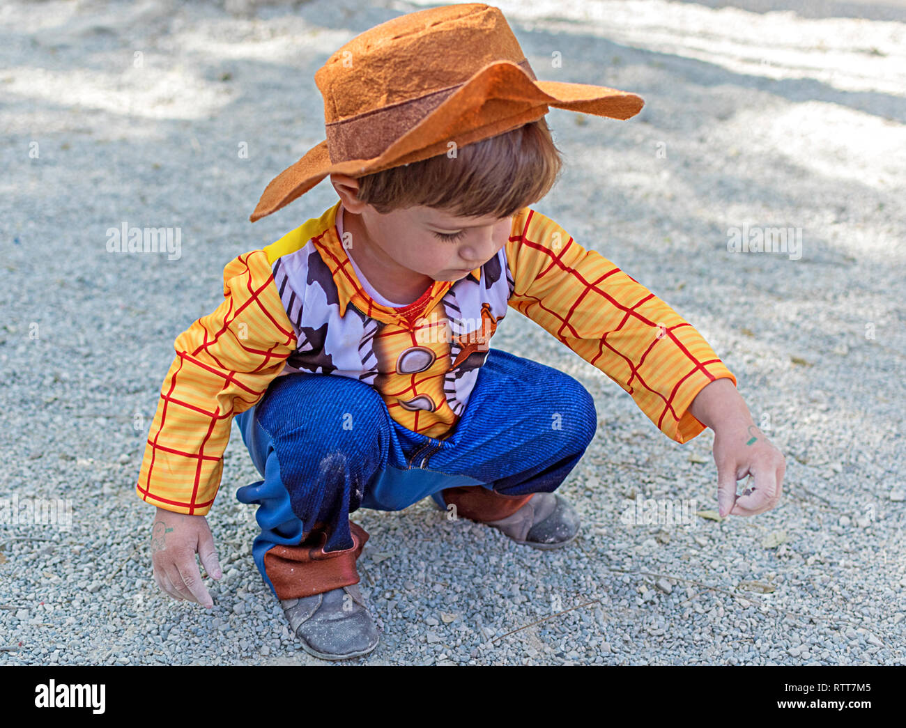 Kleines Kind, Kind, Kinder tragen Woody Toy Story Kostüm spielen auf dem Boden mit dem Schmutz und Sand, die schmutzigen Hände. Kindheit Kreativität in Spanien im Jahr 2019. Stockfoto