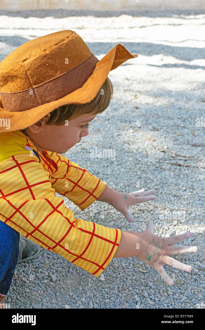 Kleines Kind, Kind, Kinder tragen Woody Toy Story Kostüm spielen auf dem Boden mit dem Schmutz und Sand, die schmutzigen Hände. Kindheit Kreativität in Spanien im Jahr 2019. Stockfoto