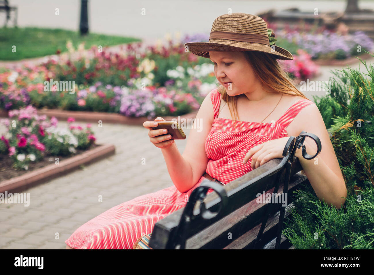Jugendlicher Mädchen verwendet Ihr Telefon im Park sitzt auf der Bank Stockfoto